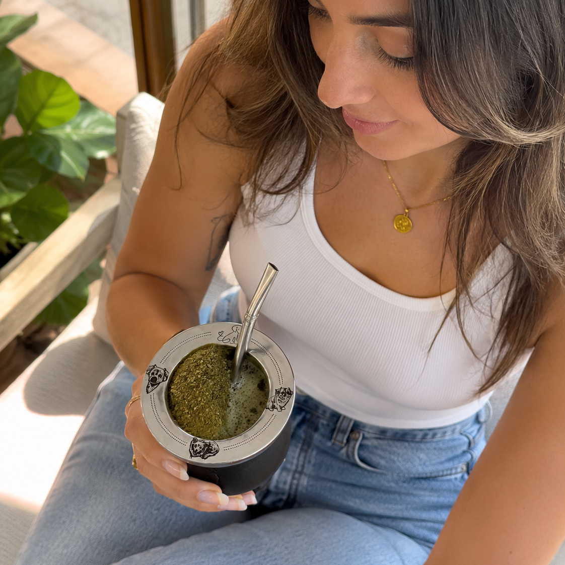Mujer tomando mate en su living con la virola grabada con las caras de sus perros